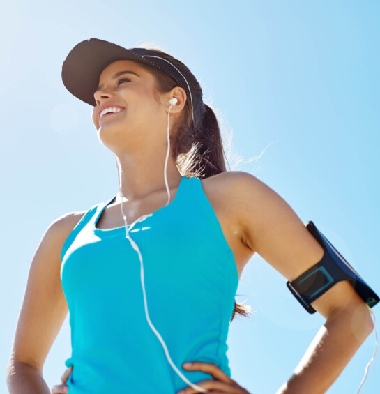 woman exercising outside wearing hat and listening to music